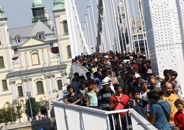 Migranti attraversano a piedi il ponte Erzsebet a Budapest (ANSA)