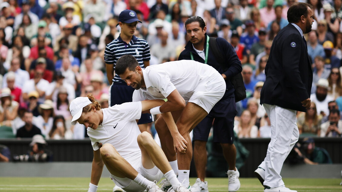 Novak Djokovic aiuta lo sfidante Jannik Sinner a terra durante un match a Wimbledon nel 2022 © ANSA/EPA