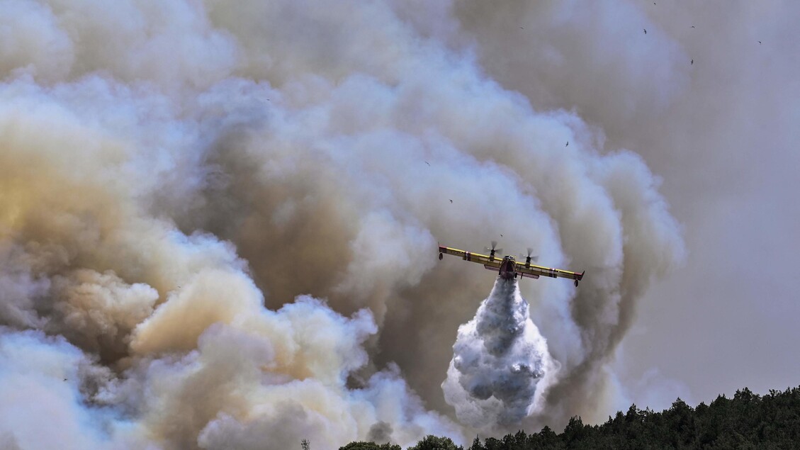 Un aereo antincendio Canadair spruzza acqua durante un incendio a Dervenochoria, nord-ovest di Atene © ANSA/AFP