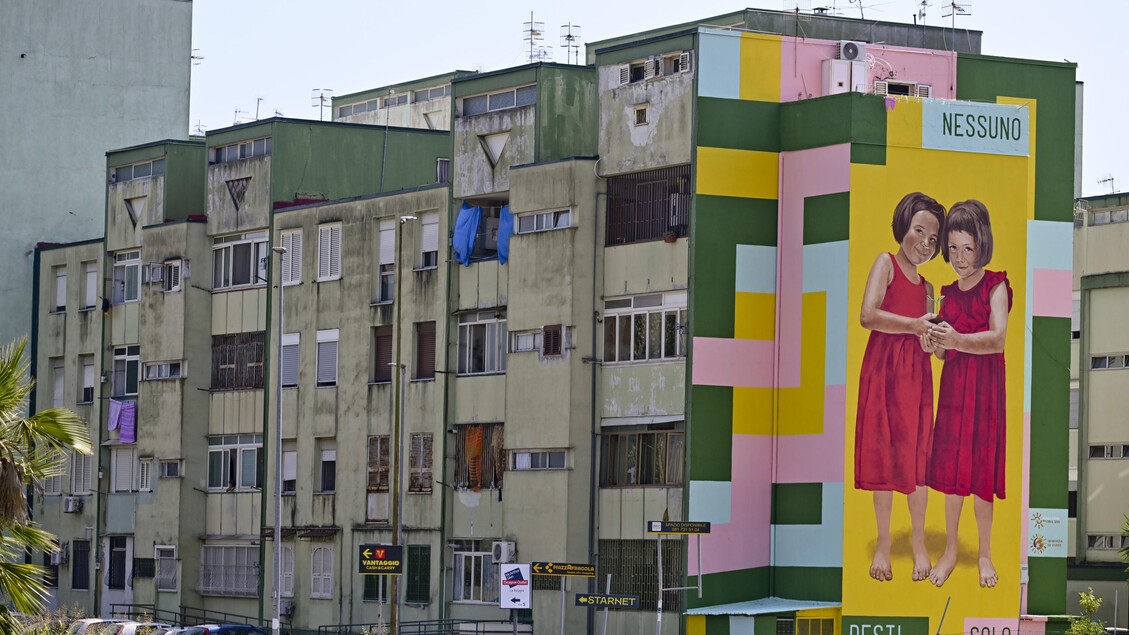 Il murale che ritrae due bambine da il benvenuto al Parco Verde di Caivano (Napoli)