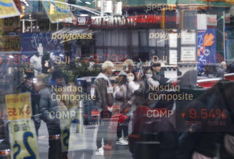 Una vetrina a Times Square a New York riflette i valori della Borsa americana mostrati da uno schermo © EPA