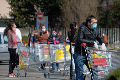 Persone in fila a un supermercato © ANSA