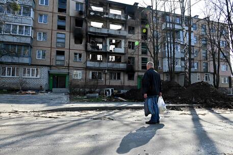 Un uomo davanti ad un palazzo colpito dalle bombe a Kharkiv © AFP