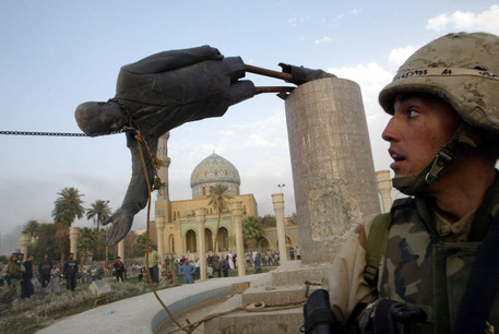 Un militare statunitense osserva la caduta della statua simbolo della capitale e del regime di Saddam Hussein il 9 Aprile 2003 nel centro di Baghdad © ANSA