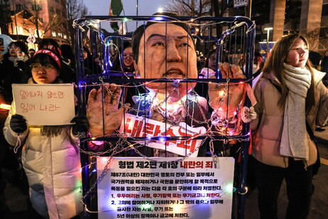 Protesters walk while displaying a chained effigy depicting impeached South Korean President