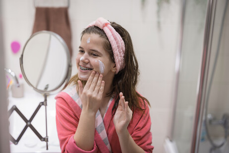 Una giovane prova una crema sul viso foto iStock.