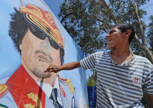 I ribelli si imposessano della caserma del Reggimento 32, guidata da Khamis Gheddafi, e danneggiano immagini del Rais © ANSA