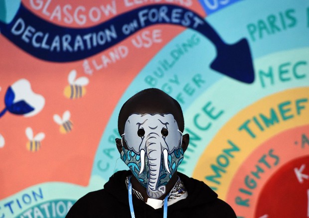Un attivista a Glasgow indossa una maschera durante una manifestazione durante la COP26© AFP>