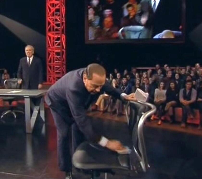 Berlusconi mentre pulisce la sedia dove era stato seduto il giornalista Marco Travaglio durante la trasmissione "Servizio pubblico" di Michele Santoro su La7 - RIPRODUZIONE RISERVATA