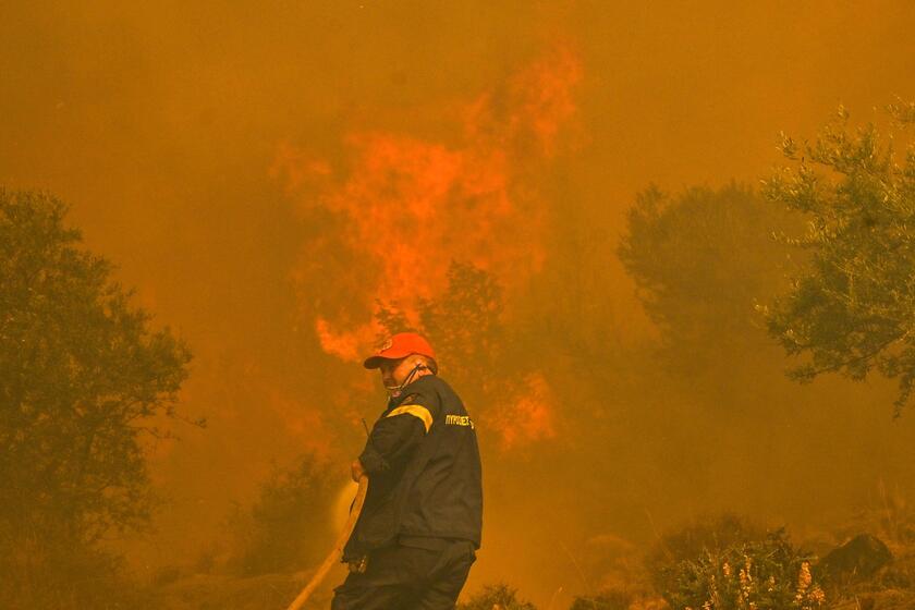 Un vigile del fuoco davanti alle fiamme di un incendio a New Peramos, vicino ad Atene © ANSA/AFP