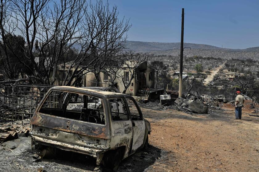 Un uomo guarda la sua proprietà bruciata, vicino a Mandra, a ovest di Atene © ANSA/AFP