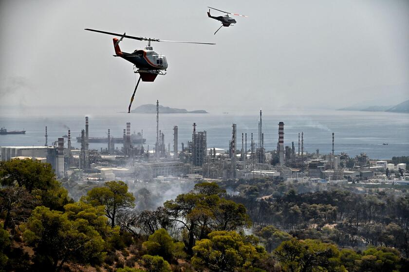 Elicotteri antincendio sorvolano un incendio vicino a una raffineria di petrolio ad Agioi Theodoroi, © ANSA/AFP