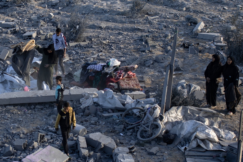 Palestinians inspect the remains of destroyed buildings in Khan Younis