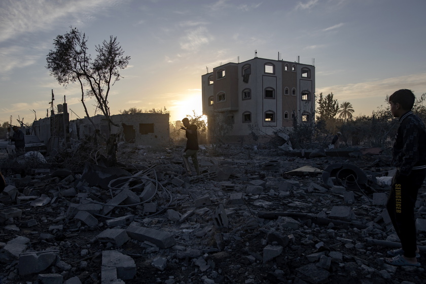 Palestinians inspect the remains of destroyed buildings in Khan Younis