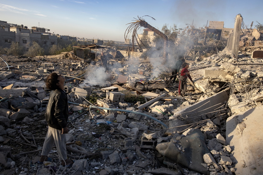 Palestinians inspect the remains of destroyed buildings in Khan Younis