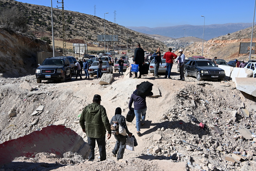 People walk at Masnaa border crossing damaged by Israeli military strike in Lebanon