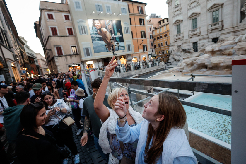 Fontana di Trevi senza acqua per il restauro, turisti lanciano monete in una vasca