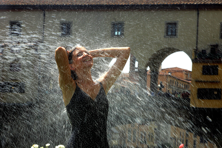 Una ragazza si  rinfresca con l 'acqua vicino a Ponte Vecchio, a Firenze - RIPRODUZIONE RISERVATA