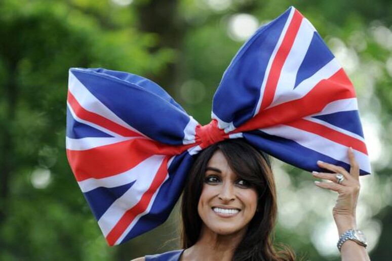 Un 'ospite della Royal Ascot, indossa un cappellino a forma di fiocco con i colori della bandiera inglese - RIPRODUZIONE RISERVATA