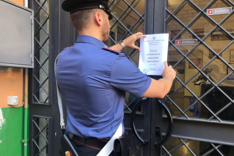 Un carabiniere appone i sigilli a un locale sequestrato nell 'operazione contro il  'clan Casamonica ' - RIPRODUZIONE RISERVATA