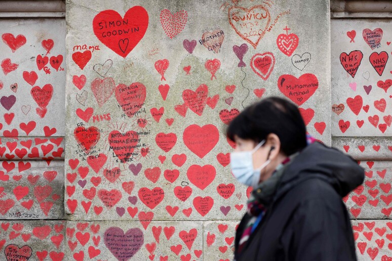 Una donna passa davanti al Muro della memoria, con 150mila cuori rossi, dedicato alle vittime del Covid a Londra © ANSA/AFP