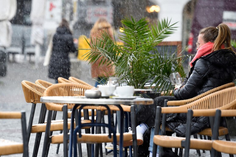 Una donna seduta ad un tavolino di un bar consuma un drink © ANSA/AFP