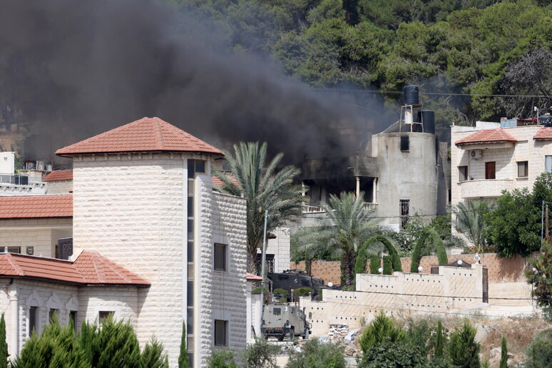Israeli military vehicle near a building on fire during an Israeli military operation in Jenin © ANSA/EPA