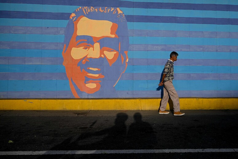 A man walks past a mural depicting Venezuelan President Nicolas Maduro © ANSA/AFP